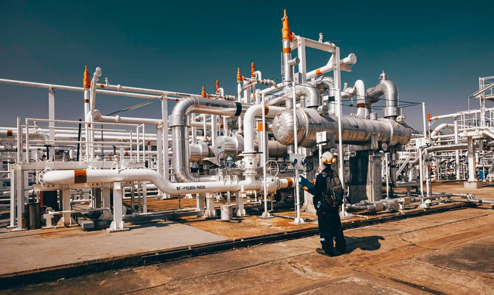 Industrial petrochemical process plant showing pipework, vessels and worker on site